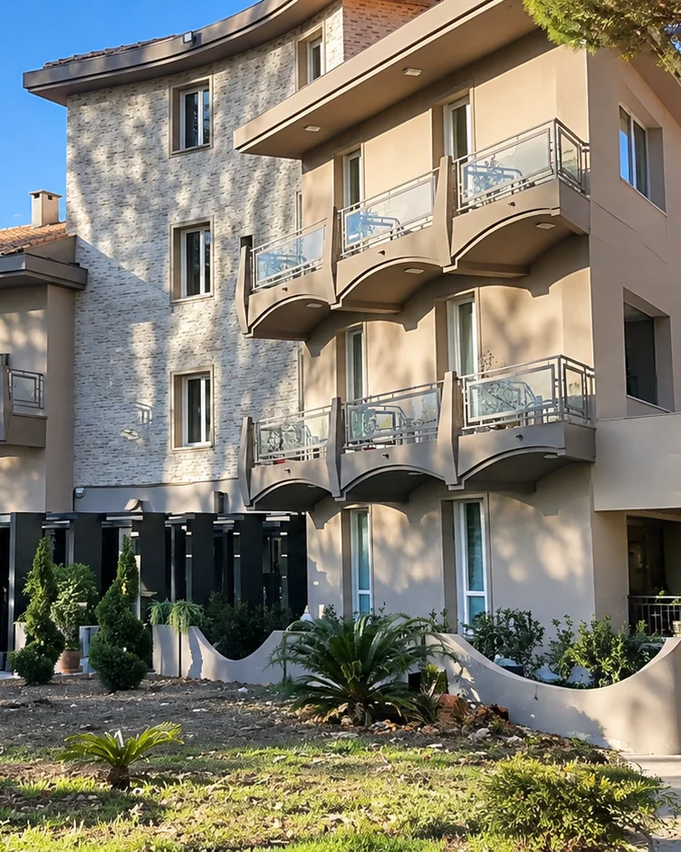 The façade of Hotel Emma Bologna, curved balconies stepping along a stone-clad front under a clear sky