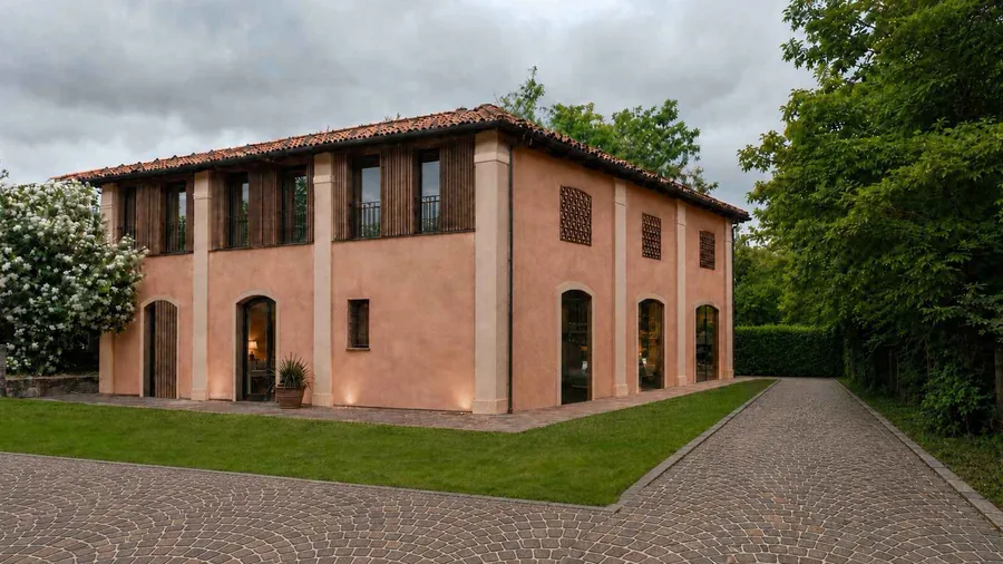 The restored building B at Residenze nel Parco, its arched ground floor and timber-slatted upper floor seen from the garden
