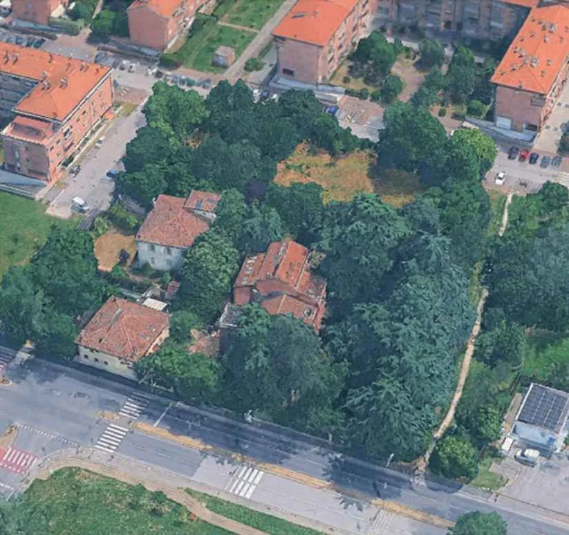 Aerial view of the site: two tiled-roof villas among mature trees at the corner of Viale Lenin, with apartment blocks around