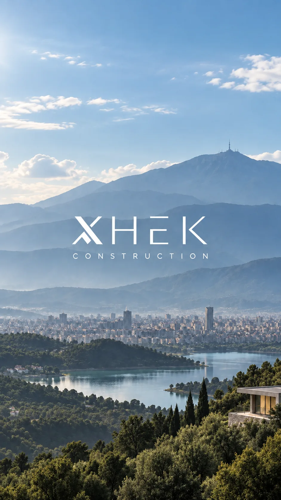The Xhek Construction mark set over a view across a lake and a city's rooftops to the mountains beyond